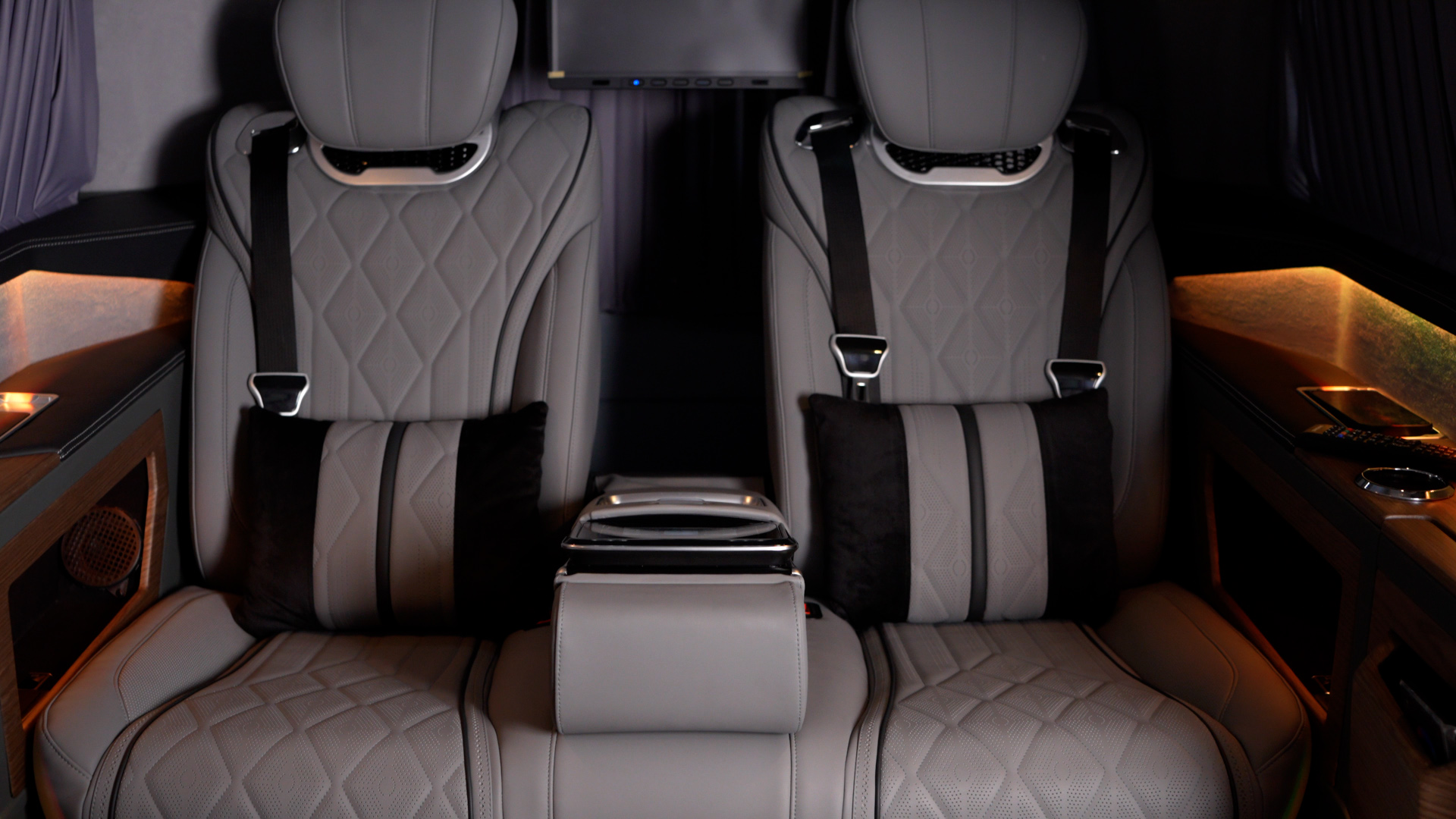 Two reclining leather seats inside the Ilesbus Vito VIP with warm ambient lighting
